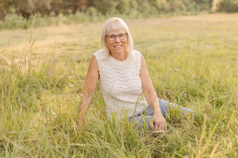 Isabelle Dulac sitting in a sunlit meadow of tall grass